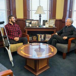 Fr. John Jenkins and Andrew Daigneau sit across from each other in Fr. Jenkins' office