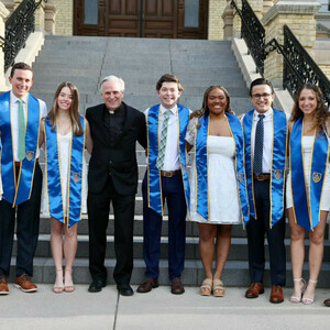 Rev. John I. Jenkins, C.S.C., stands with a group of students near the steps of the Main Building
