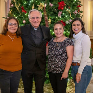 Fr. Jenkins stands with three staff members in front of a Christmas tree in the Main Building