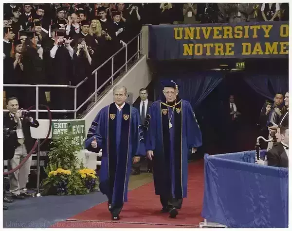 Rev. Malloy walking with President George W. Bush during commencement ceremony